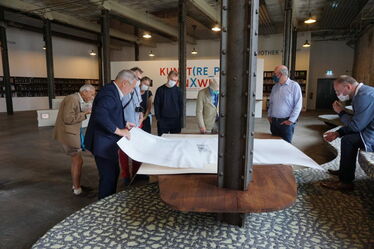 Ingo Fischer erklärt den Exkursionsteeilnehmern in der Besucherhalle der Baumwollspinnerei anhand von Plänen die denkmalpflegerische Konzeption